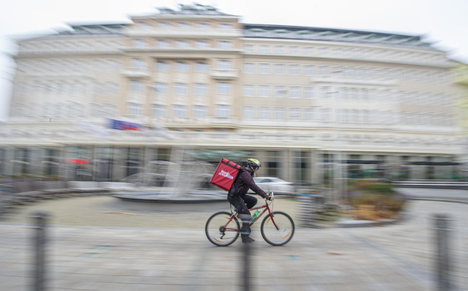 A courier delivers food in the old town of Bratislava, Slovakia, Thursday, Nov. 25, 2021. The Slovak government approved a two-week national lockdown amid a record surge of coronavirus infections. Prime Minister Eduard Heger said the measures, effective from Thursday, will target all, both unvaccinated and vaccinated. (Martin Baumann/TASR via AP)