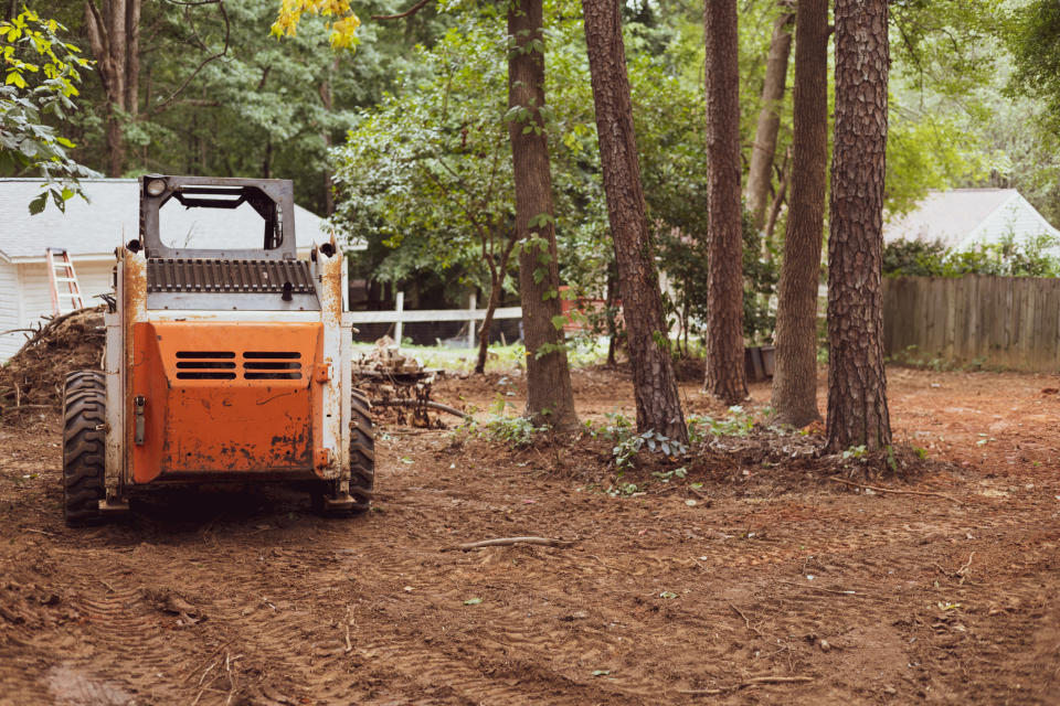 A bulldozer parked in a residential yard with some trees around it, likely for construction or landscaping work