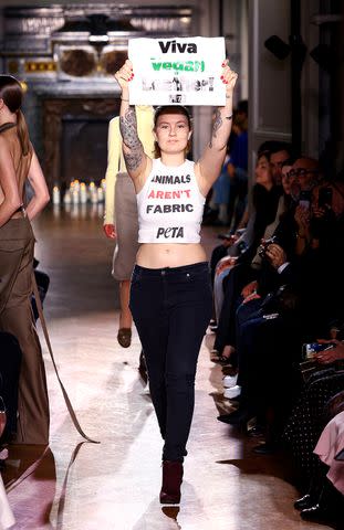 <p>Marc Piasecki/WireImage</p> A protestor is seen at Victoria Beckham's Paris Fashion Week show