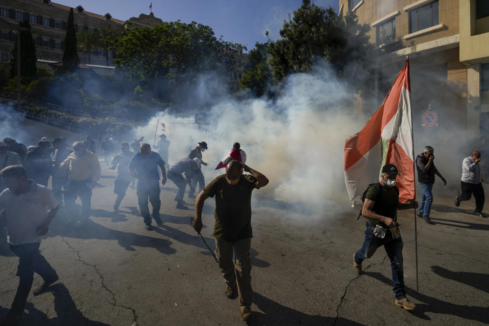 Retired members of Lebanese security forces and other protesters run from tear gas after clashing with the Lebanese army and riot police during a protest in Beirut, Lebanon, Tuesday, April 18, 2023. Earlier in the day, Lebanon's Parliament voted to postpone municipal elections in the crisis-stricken country that had been planned for May 2023 by up to a year. (AP Photo/Hassan Ammar)