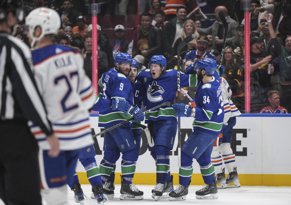 Vancouver Canucks' J.T. Miller, Quinn Hughes, Brock Boeser and Phillip Di Giuseppe, from left, celebrate a goal by Boeser against the Edmonton Oilers during the second period of an NHL hockey game Wednesday, Oct. 11, 2023, in Vancouver, British Columbia. (Darryl Dyck/The Canadian Press via AP)