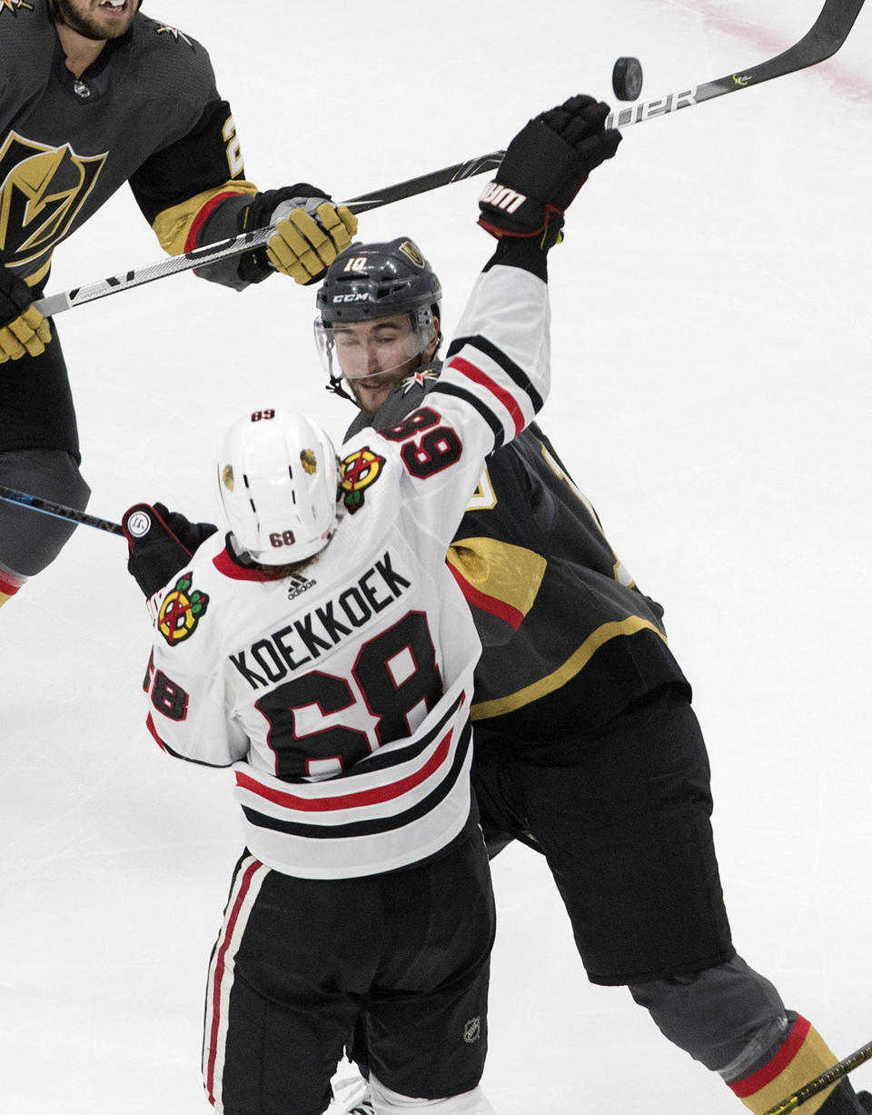 Vegas Golden Knights' Nicolas Roy (10) and Chicago Blackhawks' Slater Koekkoek (68) reach for the loose puck during the third period of an NHL hockey Stanley Cup first-round playoff series, Thursday, Aug. 13, 2020, in Edmonton, Alberta. (Jason Franson/The Canadian Press via AP)
