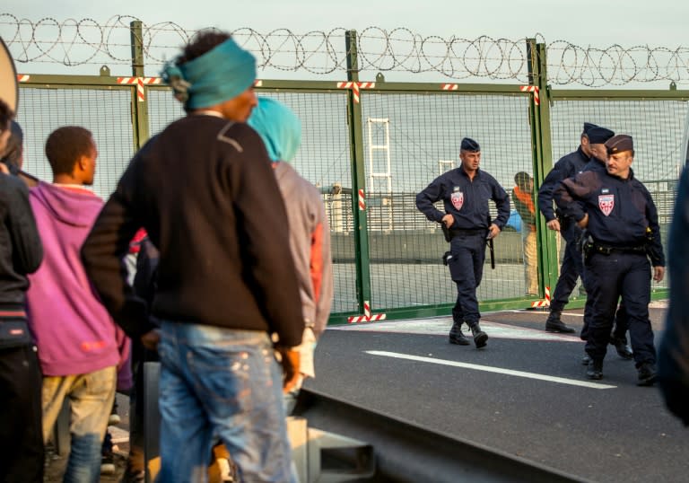 Migrants, who managed to get past roadblocks set up by French gendarmes inside the Eurotunnel site, wait outside the closed entrance of the boarding platform as French gendarmes monitor them, in Coquelles near Calais, France, on July 31, 2015