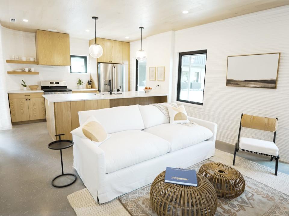 a white couch in a living room with the kitchen in the rear