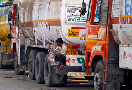 FILE PHOTO: A driver reads a newspaper as he sits on a spare tire attached to a parked oil tanker at a truck terminal in Mumbai, India, January 10, 2018. REUTERS/Shailesh Andrade/File Photo