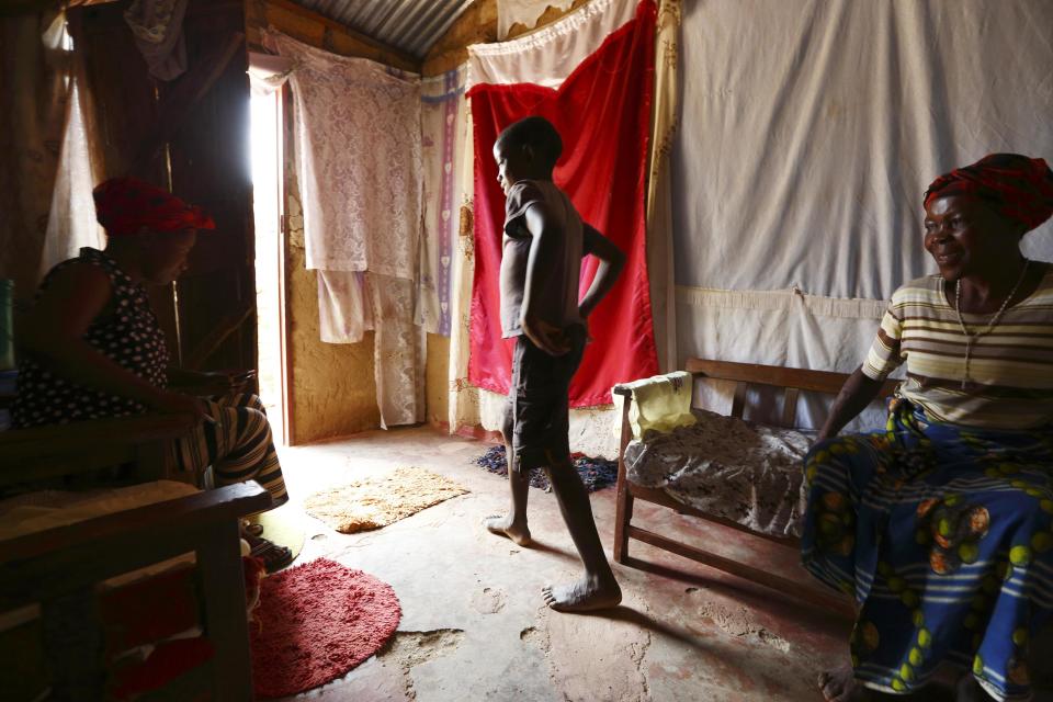 Andrew Kabuli, un niño de 12 años con VIH, sale de la habitación durante la visita de Stembisiwe Peme (i), la coordinadora del programa, que está sentada cerca de la madre del pequeño, en Chikuni.