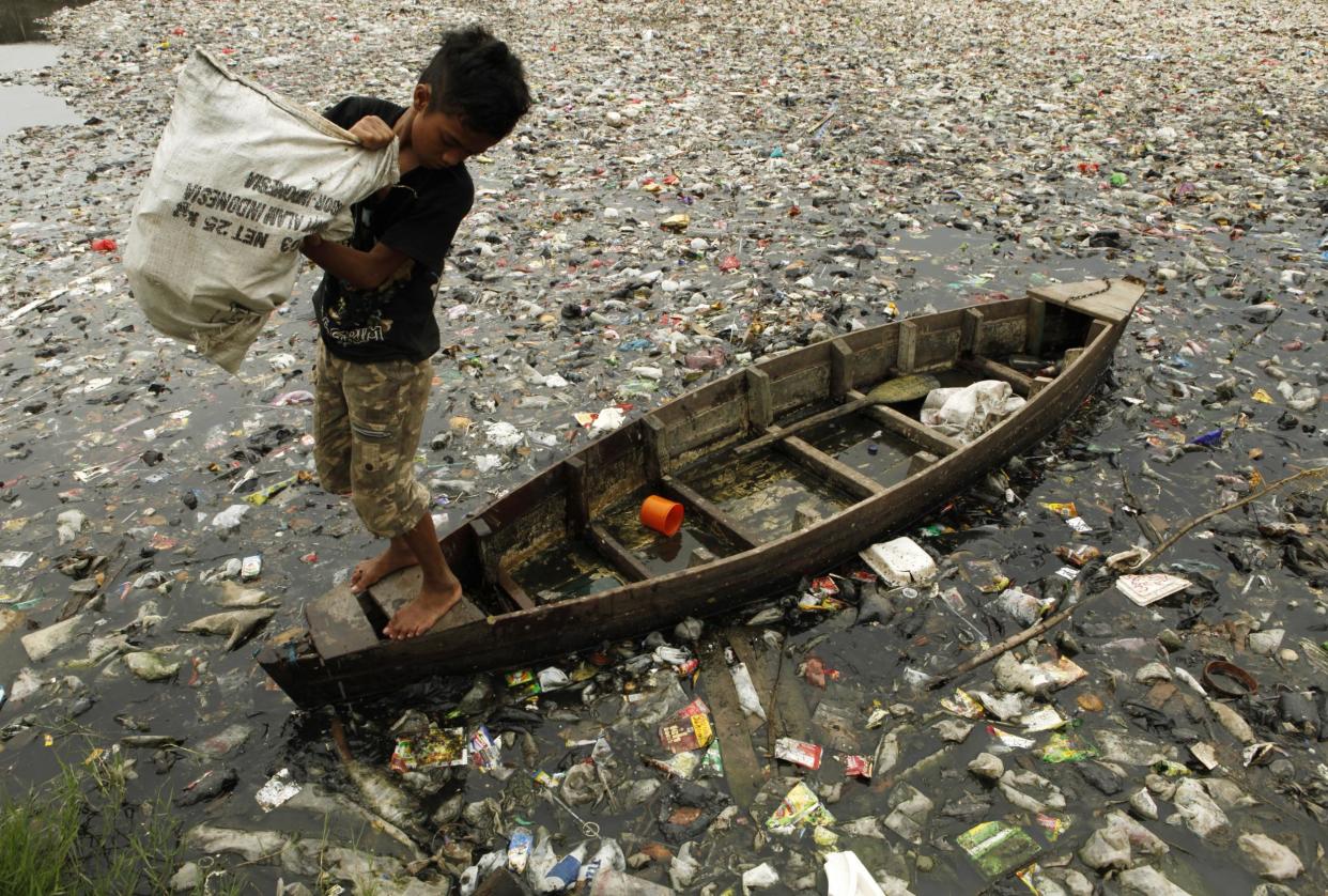 A child collects plastic cups from a polluted river in Jakarta: Beawiharta/Reuters