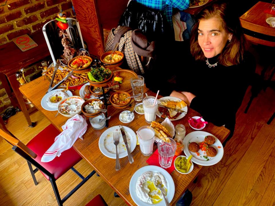 A woman next to a table full of dishes at a restaurant