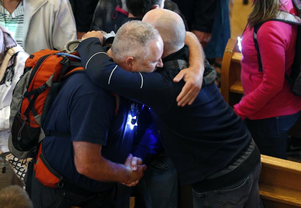 People hug each other during Messe Reconfort at Sainte-Agnes church in Lac-Megantic