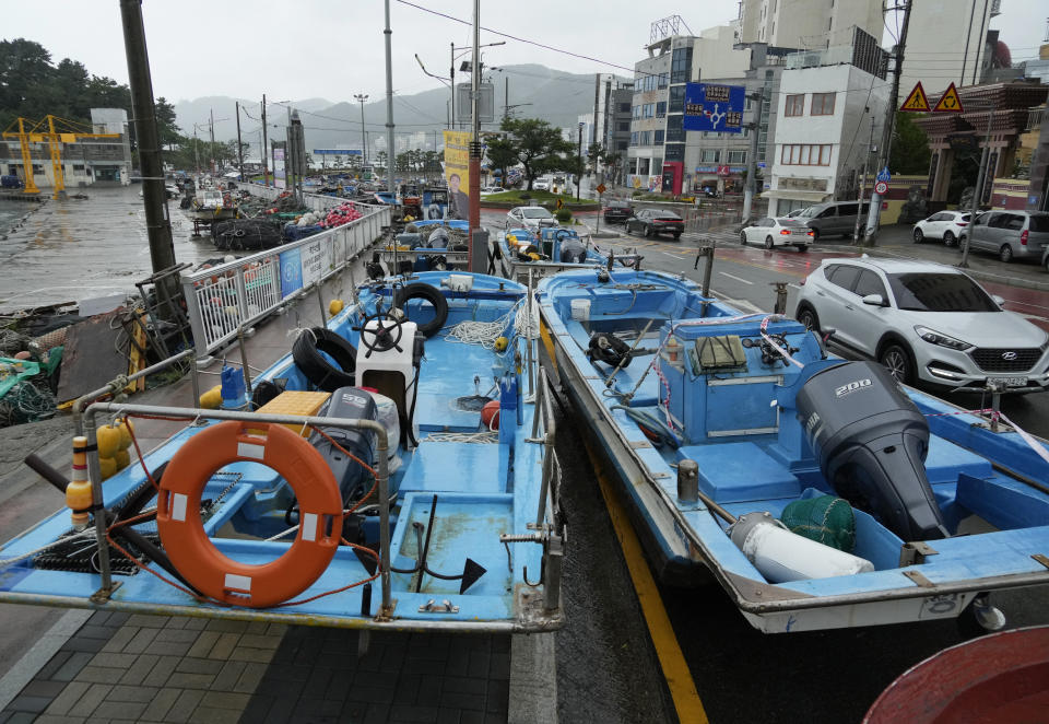 Fishing boats are placed along a road as the tropical storm named Khanun approaches to the Korean Peninsular, in Busan, South Korea, Wednesday, Aug. 9, 2023. Dozens of flights and ferry services were grounded in South Korea on Wednesday ahead of the tropical storm that has dumped heavy rain on Japan's southwestern islands for more than a week. (AP Photo/Ahn Young-joon)