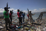 Flanked by members of the G9 gang coalition, leader Jimmy Cherizier, aka Barbecue, right, talks to reporters near the perimeter wall that encloses Terminal Varreux, the port owned by the Mevs family, in Port-au-Prince, Haiti, Wednesday, Oct. 6, 2021. Barbecue, a former policeman, fancies himself a man of the people and an enemy of the elite. (AP Photo/Rodrigo Abd)