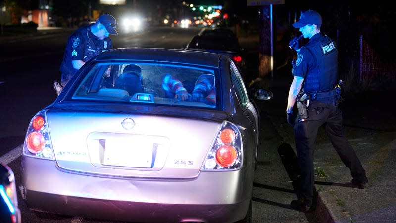 Gresham Police Sgt. Travis Garrison, left, and Officer Ryan Gomez look inside a vehicle during a traffic stop in Gresham, Ore., Thursday, July 21, 2022.