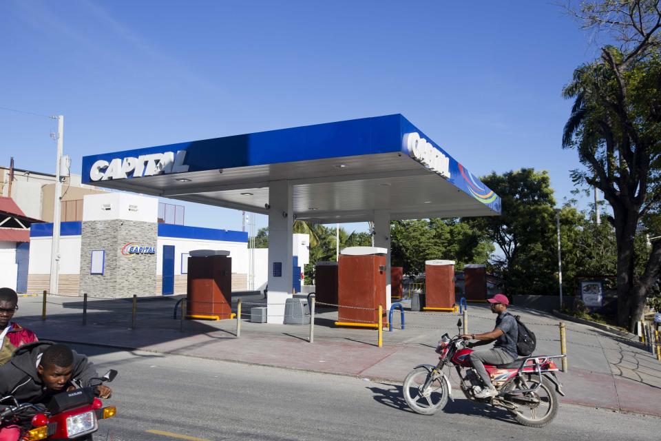 A motorcyclist rides past a closed gas station on the third day of a strike and of countrywide protests over allegations of government corruption, in Port-au-Prince, Haiti, Tuesday, Nov. 20, 2018. Demonstrators are calling for the president to resign for not investigating allegations of corruption in the previous government over a Venezuelan subsidized energy program, Petrocaribe. (AP Photo/Dieu Nalio Chery)