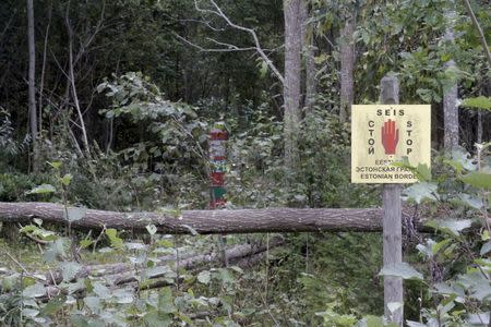 A Russian border marker (L) and an Estonian warning sign are pictured near the Estonian-Russian border, where, according to Estonia's officials, its security officer Eston Kohver was abducted in the south-east part of country, near the village of Miikse, Estonia, in this September 7, 2014 file picture. REUTERS/Ints Kalnins/Files