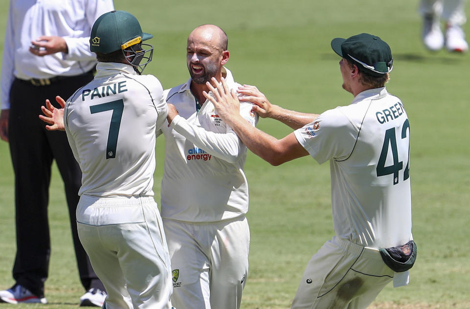 Australia's Nathan Lyon, centre, is congratulated by teammates Tim Paine, left, and Cameron Green after taking the wicket of India's Shubman Gill for 91 runs during play on the final day of the fourth cricket test between India and Australia at the Gabba, Brisbane, Australia, Tuesday, Jan. 19, 2021. (AP Photo/Tertius Pickard)