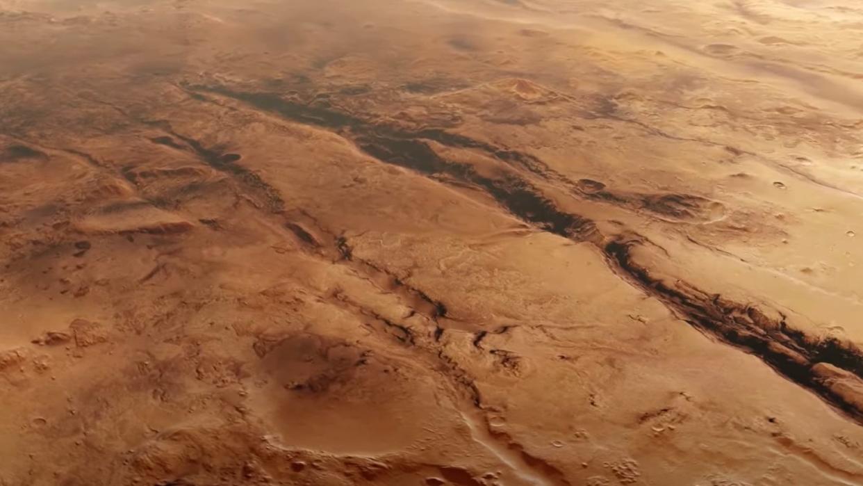  A reddish-orange landscape lined with deep trenches and ravines. 