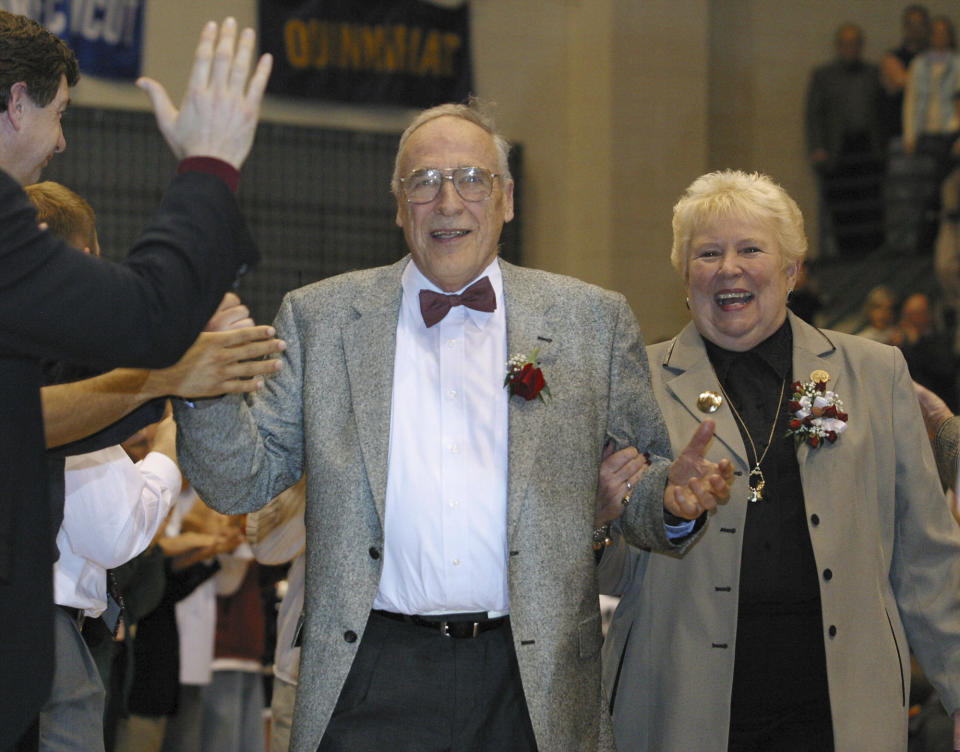 FILE - Mount St. Mary's men's NCAA college basketball coach Jim Phelan and his wife Dottie walk through a gauntlet of former players at Knott Arena in Emmitsburg, Md., after Phelan coached his last game as coach, in this Saturday, March 1, 2003, file photo. Phelan, the bow-tied basketball coach who won 830 games during nearly a half-century at Mount St. Mary's, has died. He was 92. The athletic department at Mount St. Mary's said Phelan died in his sleep at home Tuesday night, June 15, 2021. (AP Photo/Timothy Jacobsen, File)