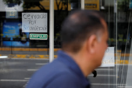 A man walks past a closed store with a placard that reads "Closed for reconversion", in reference to the monetary conversion, at a commercial area in Caracas, Venezuela August 21, 2018. REUTERS/Carlos Garcia Rawlins