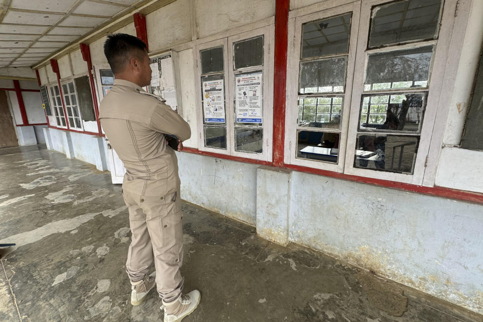 A policeman looks at election posters at a polling station on the eve of polling in Chedema village, in the northeastern Indian state of Nagaland, Thursday, April 18, 2024. (AP Photo/Yirmiyan Arthur)