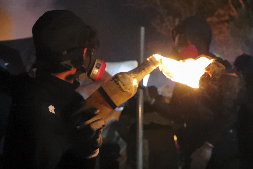 In this Tuesday, Nov. 12, 2019, file photo, a student holds a molotov cocktail during clashes at the Chinese University in Hong Kong. Protesters who barricaded themselves inside Hong Kong’s universities have tried to turn the campuses into armed camps, resorting to medieval weapons to stop police from entering the grounds. Their weapons include bows and arrows, catapults and hundreds of gasoline bombs stacked up to ramparts - often built by the students. (AP Photo/Kin Cheung, File)