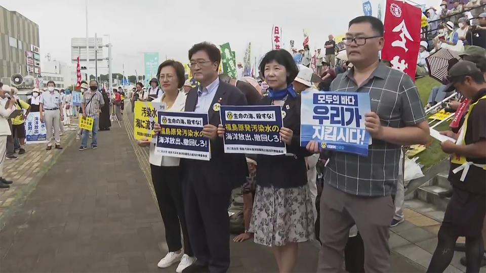 In this image made from video, South Korean lawmakers from left, Kang Eun-mi, Woo Wonshik and Yang Jung-suk, hold placards which reads "Withdraw the discharge of the wastewater from Fukushima nuclear power plant into the ocean" during a protest in Iwaki, Fukushima prefecture, Sunday, Aug. 27, 2023. South Korean lawmakers attended a protest in Iwaki in Fukushima prefecture against the release of treated radioactive wastewater from the region's crippled nuclear plant into the ocean. (AP Photo)