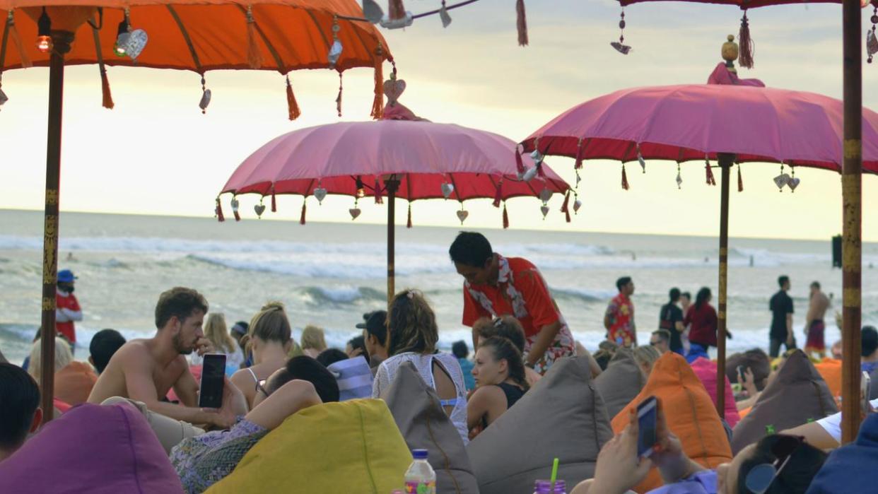 Tourists lounging on bean bags by the beach in Seminyak