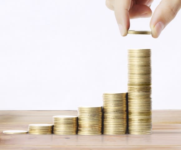 a hand stacks coins in ascending stacks.