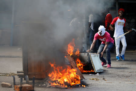 A protester pushes an old refrigerator into a burning barricade during a march to demand an investigation into what they say is the alleged misuse of Venezuela-sponsored PetroCaribe funds, in Port-au-Prince, Haiti, October 17, 2018. REUTERS/Andres Martinez Casares