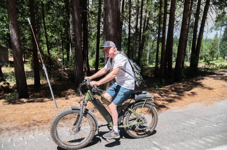 Bryan Morey, who has lived in the area for 32 years, bikes along the road near Forest Ranch on Friday, July 26, 2024.“I’m all hitched up with stuff and ready to go, and I know several evacuation corridors,” said Morey, who has yet to evacuate. “But I will run if it gets too close.”