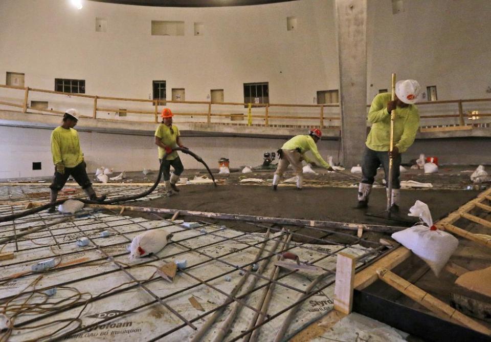 In this Thursday, Dec. 8, 2016 photo, workers pour concrete at the Patricia and Phillip Frost Museum of Science under construction in Miami. Rising next to Miami's spiffy new bayside art museum is a $305 million science museum that, like South Florida, is focused in large part on water: its centerpiece is a 500,000-gallon aquarium that will feature sharks, tuna, mahi-mahi and even sea turtles, with other smaller tanks for corals and other sea life. The Frost Science Museum, scheduled to open this spring. (AP Photo/Wilfredo Lee)