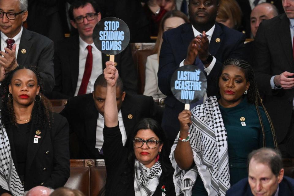 Rashida Tlaib and Cori Bush hold signs saying "Stop sending bombs" and "Lasting ceasefire now" at the 2024 State of the Union