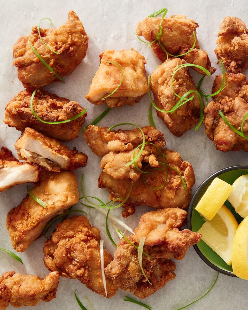 fried chicken karaage garnished with shaved green onions and a bowl of lemon wedges