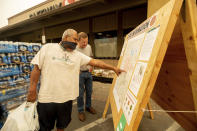 As new evacuation orders take effect for the Dixie Fire, Carlos Duran, left, and Rich McFeely examine a fire map in Quincy, Calif., on Sunday, July 25, 2021. (AP Photo/Noah Berger)