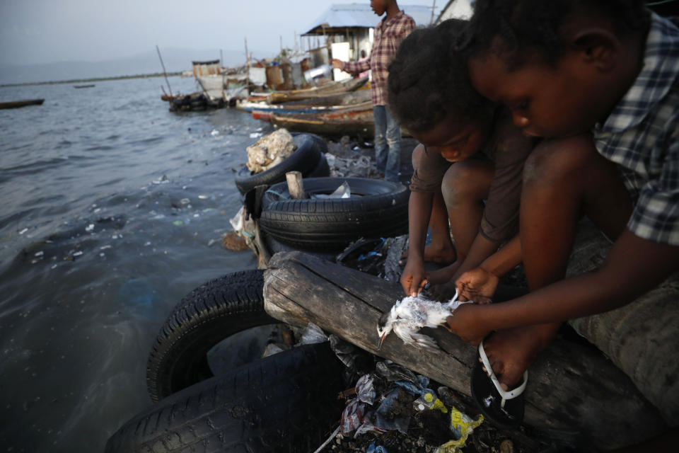 Cousins, ages 8 and 10, pluck a small bird before chopping off the wings and head to prepare it to be cooked, in the Cite Soleil neighborhood of Port-au-Prince, Haiti, Thursday, Oct. 10, 2019. Residents of Cite Soleil say their already limited access to basic services, work, and security has only been declining, and many are participating in the protests calling for the resignation of President Jovenel Moise. (AP Photo/Rebecca Blackwell)