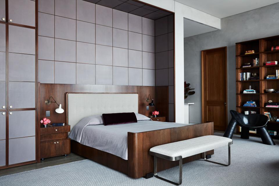 Lambskin panels in a walnut frame line the walls of the primary bedroom. Headboard upholstered in a Sam Kasten handweaver silk, bench by Milo Baughman, and chair by Wendell Castle.