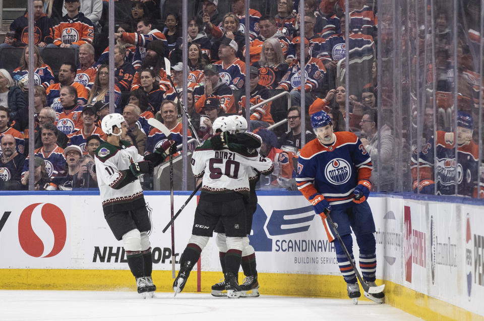 Arizona Coyotes' Dylan Guenther (11), Sean Durzi (50) and Logan Cooley (92) celebrate a goal as Edmonton Oilers' Warren Foegele (37) skates past during the second period of an NHL hockey game Friday, April 12, 2024, in Edmonton, Alberta. (Jason Franson/The Canadian Press via AP)