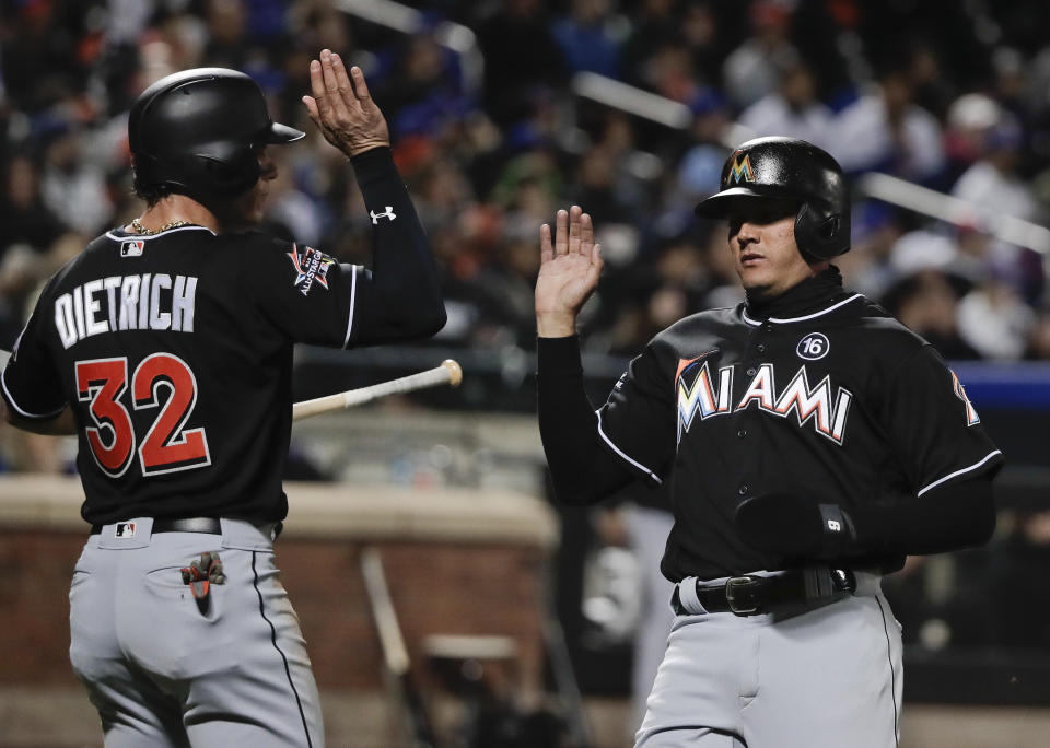 Miami Marlins' Derek Dietrich (32) greets Miguel Rojas at home plate after the two scored on a double by Dee Gordon (9) against the New York Mets during the third inning of a baseball game, Sunday, April 9, 2017, in New York. (AP Photo/Julie Jacobson)