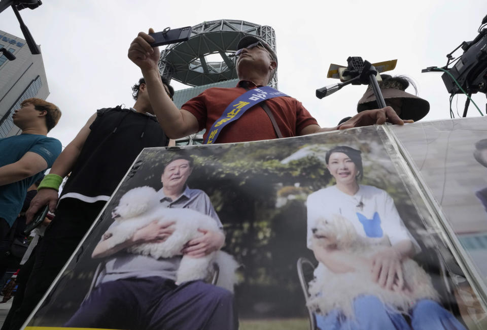 An animal rights activist with a photo showing South Korean President Yoon Suk Yeol, left, and his wife Kim Keon Hee participates in a rally opposing South Korea's traditional culture of eating dog meat in Seoul, South Korea, Saturday, July 8, 2023. In April, first lady Kim Keon Hee, the wife of current President Yoon Suk Yeol, said in a meeting with activists that she hopes for an end to dog meat consumption. Farmers responded with rallies and formal complaints against Kim for allegedly hurting their livelihoods. (AP Photo/Ahn Young-joon)