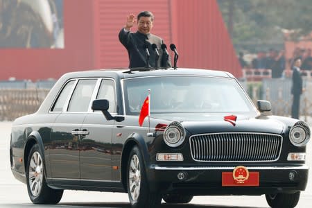 Chinese President Xi Jinping waves from a vehicle as he reviews the troops at a military parade marking the 70th founding anniversary of People's Republic of China