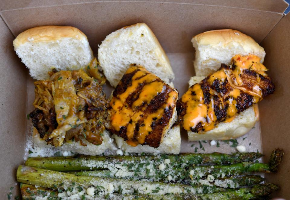 An order of a pulled pork slider (left) and two blackened snapper slider specials are served with a side order of Parmesan grilled asparagus cooked by Tony Weisman in his food truck, Sunset Sliders, while parked along Southeast Dixie Highway at Southeast Hawthorn Street on Thursday, June 27, 2019, in the Golden Gate area, south of Stuart.