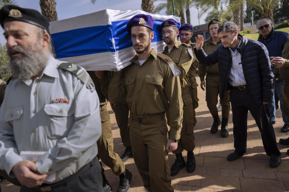 Yoram, right, father of Israeli soldier Lt. Yaacov Elian, bids farewell as soldiers carry his son's flag-draped casket during his funeral at Kiryat Shaul military cemetery in Tel Aviv, Israel, Friday, Dec. 22, 2023. Elian, 20, was killed during Israel's ground operation in the Gaza Strip, where the Israeli army has been battling Palestinian militants in the war ignited by Hamas' Oct. 7 attack into Israel. (AP Photo/Oded Balilty)