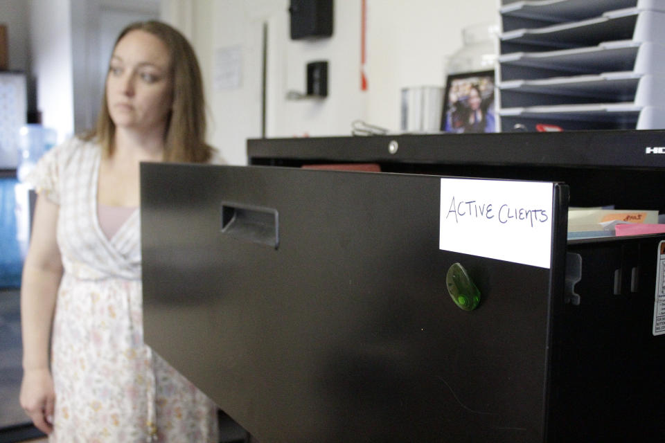 Cassie Trahan, co-founder and executive director of A Village for One, poses with a filing cabinet full of cases of sexually exploited or abused teenage girls and young women at the nonprofit in Oregon City, Oregon in this May 4, 2022 photo. Trahan says case dismissals due to an acute shortage of public defenders in Oregon is affecting her clients' mental health as cases against their abusers stall. A post-pandemic glut of delayed cases has exposed shocking constitutional landmines impacting defendants and crime victims alike in Oregon, where an acute shortage of public defenders has even led judges to dismiss serious cases. (AP Photo/Gillian Flaccus)