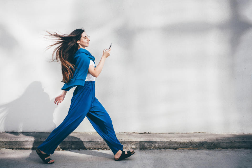 A woman walking briskly while looking at her phone