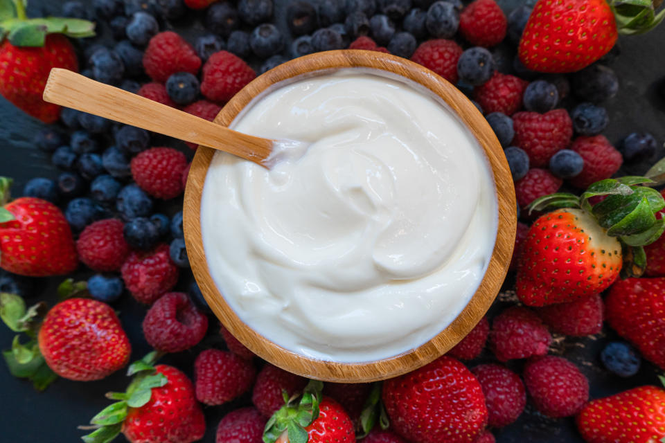 Griechischer Joghurt in einem Becher umgeben von Früchten