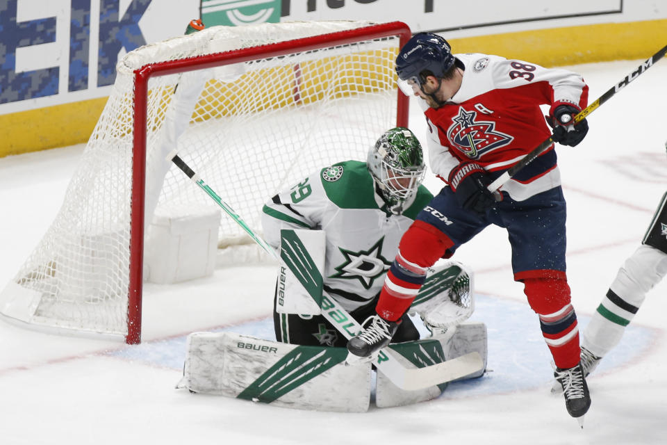 Dallas Stars' Jake Oettinger, left, makes a save against Columbus Blue Jackets' Boone Jenner during the first period of an NHL hockey game Tuesday, Feb. 2, 2021, in Columbus, Ohio. (AP Photo/Jay LaPrete)