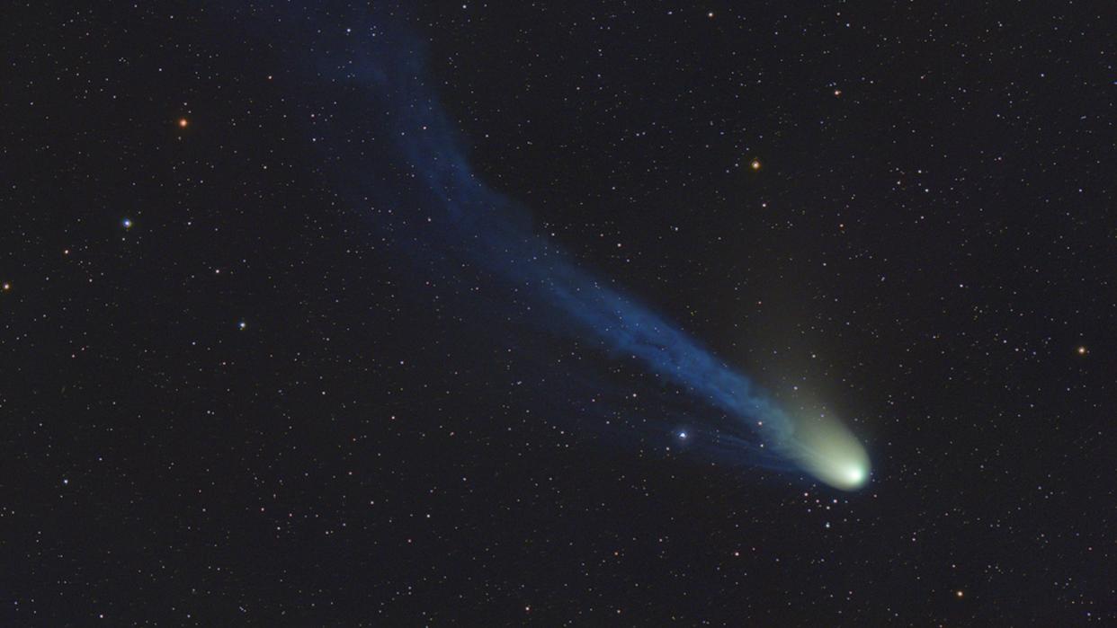  A bright dot leaves a hazy trail behind it as it flies in front of background stars. 