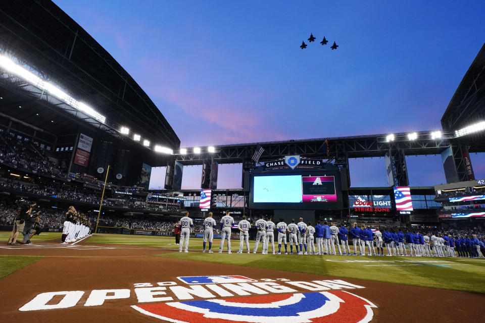 The Arizona Diamondbacks and the Los Angeles Dodgers watch a military flyover prior to a baseball game Thursday, April 6, 2023, in Phoenix. It is the Diamondbacks' home opening baseball game. (AP Photo/Ross D. Franklin)