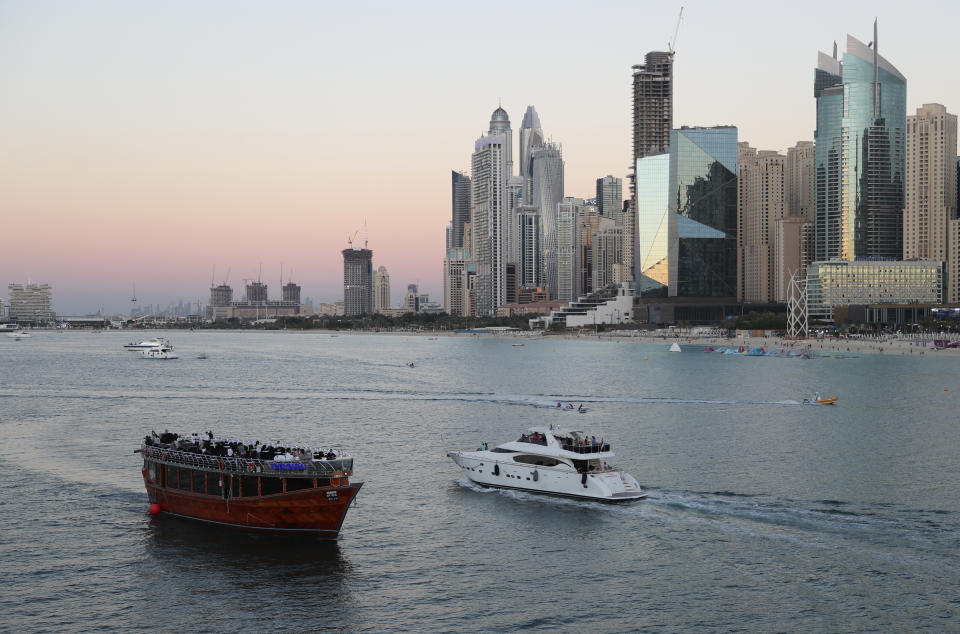 Tourists on a yacht as they pass a traditional dhow serving a dinner cruise, in Dubai, United Arab Emirates, Tuesday, Jan. 12, 2021. With peak tourism season in full swing, coronavirus infections are surging to unprecedented heights, with daily case counts nearly tripling in the past month, forcing Britain to slam shut its travel corridor with Dubai last week. But in the face of a growing economic crisis, the city won't lock down and can't afford to stand still. (AP Photo/Kamran Jebreili)
