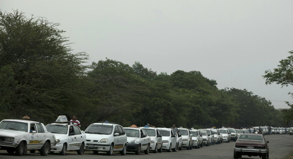 Taxi-cabs lineup to fill up on fuel near San Antonio, Venezuela, Thursday, Feb. 21, 2019. The vehicles queue for almost 2 kilometers from the gas station, as fuel sales are restricted to a couple of days per week in an attempt to control smuggling into Colombia. (AP Photo/Rodrigo Abd)