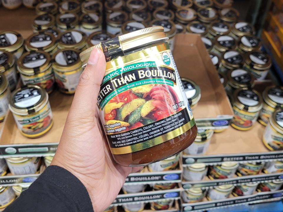hand holding a jar of better than bouillon in front of the shelves at costco